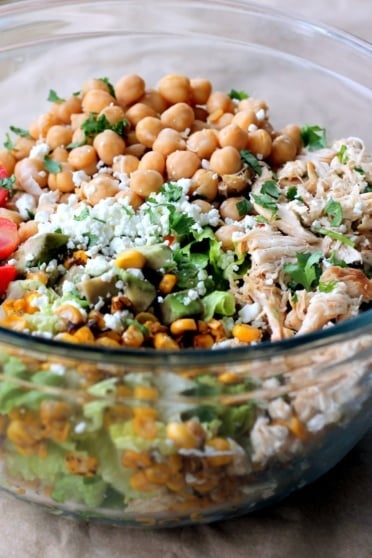 Easy healthy chicken chickpea chopped salad loaded with protein and fresh ingredients like grilled corn, grape tomatoes, crunchy romaine, creamy avocado, and your favorite dressing.