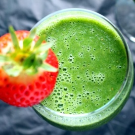 Green monster smoothie in a glass with a strawberry