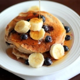 stack of oatmeal pancakes with bananas and maple syrup