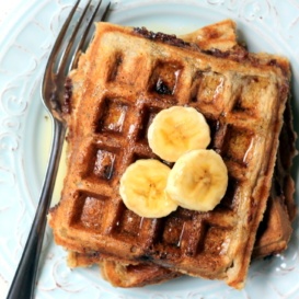 stack of waffles on plate with banana slices and maple syrup