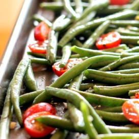 Roasted garlic parmesan green beans with tomatoes on a baking tray