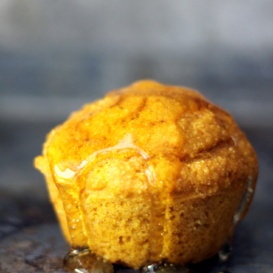 healthy pumpkin cornbread muffin drizzled with honey