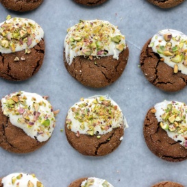 Soft ginger cookies dipped in white chocolate and pistachios on a baking tray