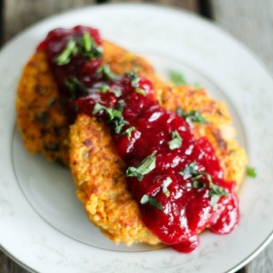 Two butternut squash quinoa patties topped with cranberry sauce on a plate
