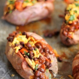 Chili stuffed sweet potatoes topped with cheese on a baking tray