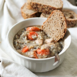 Chicken wild rice soup in a white bowl with bread