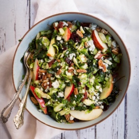 bowl of shredded brussels sprouts salad with apple, pecans, and cheese