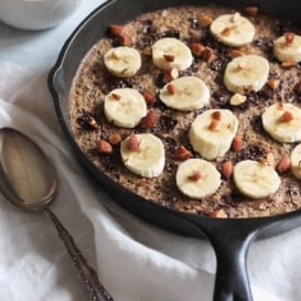 banana baked oatmeal with chocolate and roasted almonds in a skillet