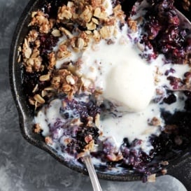 healthy blackberry crisp in a skillet with ice cream