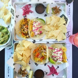 two platters of tacos and tortilla chips on a table