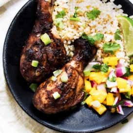 grilled jerk chicken drumsticks with rice and mango salsa in a bowl