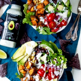 two sweet potato taco bowls next to a bottle of salad dressing