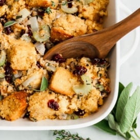 cornbread stuffing in a baking dish with a wooden spoon