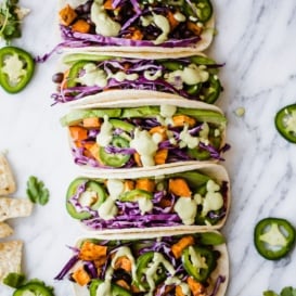 sweet potato black bean tacos lined up on a marble board