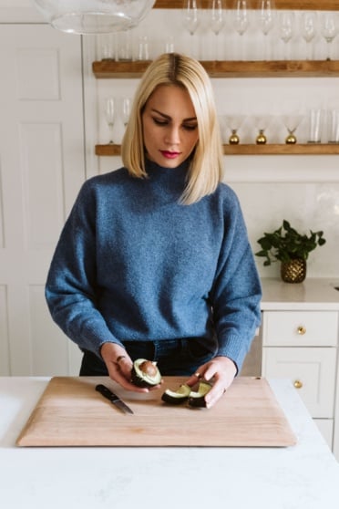 blonde woman demonstrating how to cut an avocado