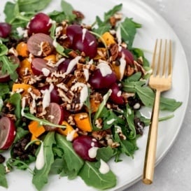 butternut squash black lentil salad with grapes on a plate with a gold fork