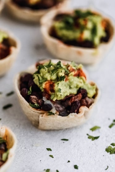 black bean taco cups with guacamole and hot sauce