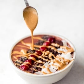 tart cherry smoothie bowl topped with peanut butter, coconut, cherries and chia seeds