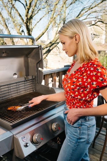 blonde woman grilling chicken breast