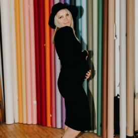 monique in a black dress in front of a rainbow curtain