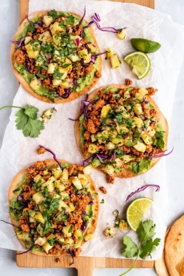 three chipotle chicken tostadas on parchment paper