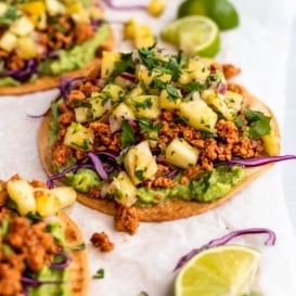 chipotle chicken tostada topped with pineapple salsa on parchment paper