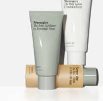 bottle of body exfoliator next to lotion and body wash
