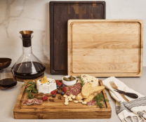 three cutting boards next to a carafe of wine