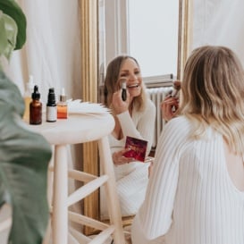 woman putting on makeup in a mirror