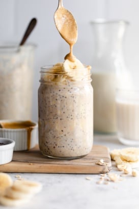 drizzling peanut butter onto a jar of peanut butter banana overnight oats