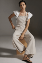 woman in overalls sitting on a stool