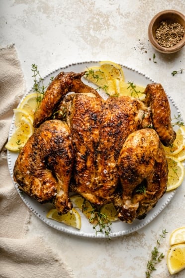 spatchcock chicken on a plate with sliced lemons