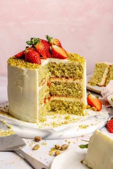 lemon pistachio cake topped with strawberries with a slice taken out