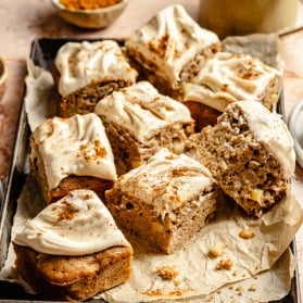 apple cake with brown butter frosting sliced on a baking pan