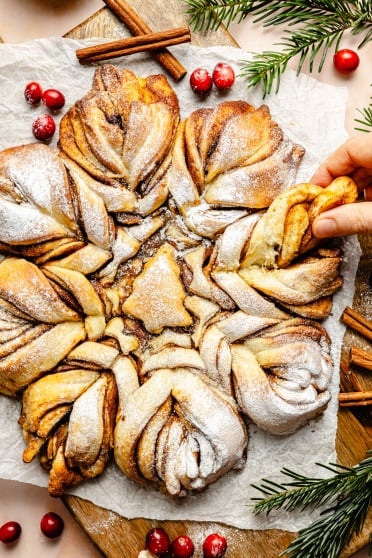 ripping off a piece of a cinnamon roll snowflake