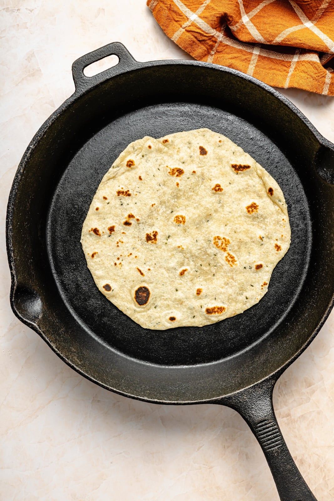 cooking a homemade flour tortilla in a cast iron skillet