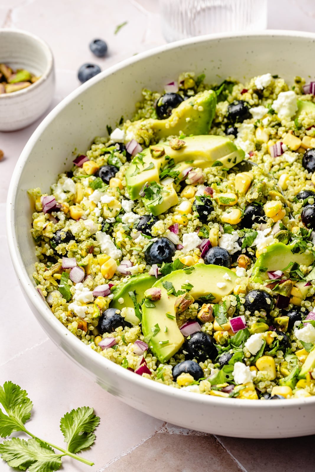 Beautiful avocado blueberry quinoa salad loaded with fresh produce, tangy feta, chopped pistachios, and tossed in a flavorful cilantro lime dressing. This delicious quinoa salad is packed with plant-based protein and is perfect for summer lunches, parties, and picnics. easy blueberry quinoa salad in a bowl