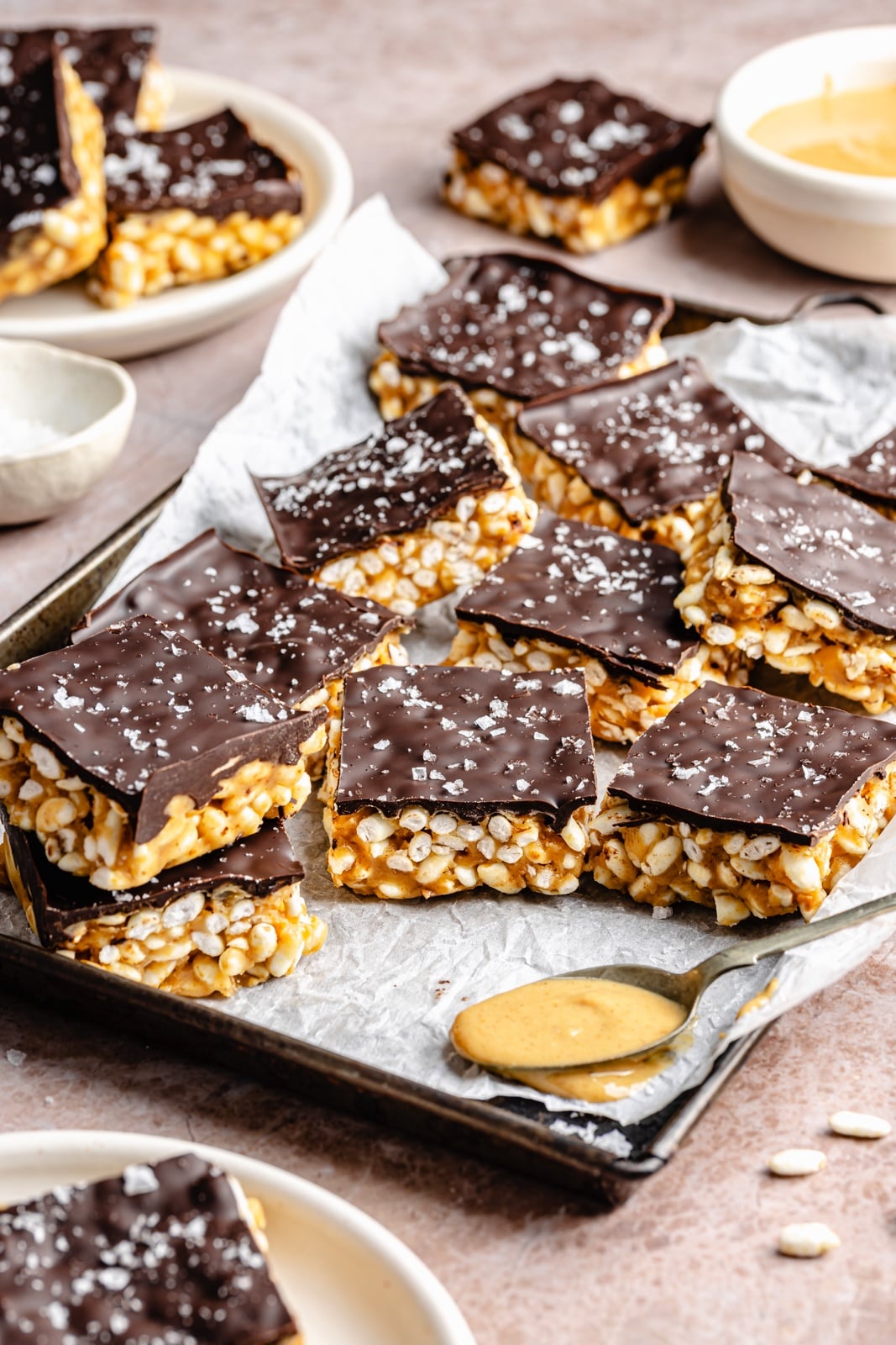 Healthy rice krispie treats made without marshmallows and with peanut butter, coconut oil, maple syrup, and brown rice krispies. These vegan and gluten-free peanut butter rice krispie treats are topped with dark chocolate and sea salt for an indulgent treat that tastes just like a crunchy peanut butter cup. Options to add a bit of protein powder to make these a great post-workout treat! gluten-free peanut butter rice krispie treats on a pan
