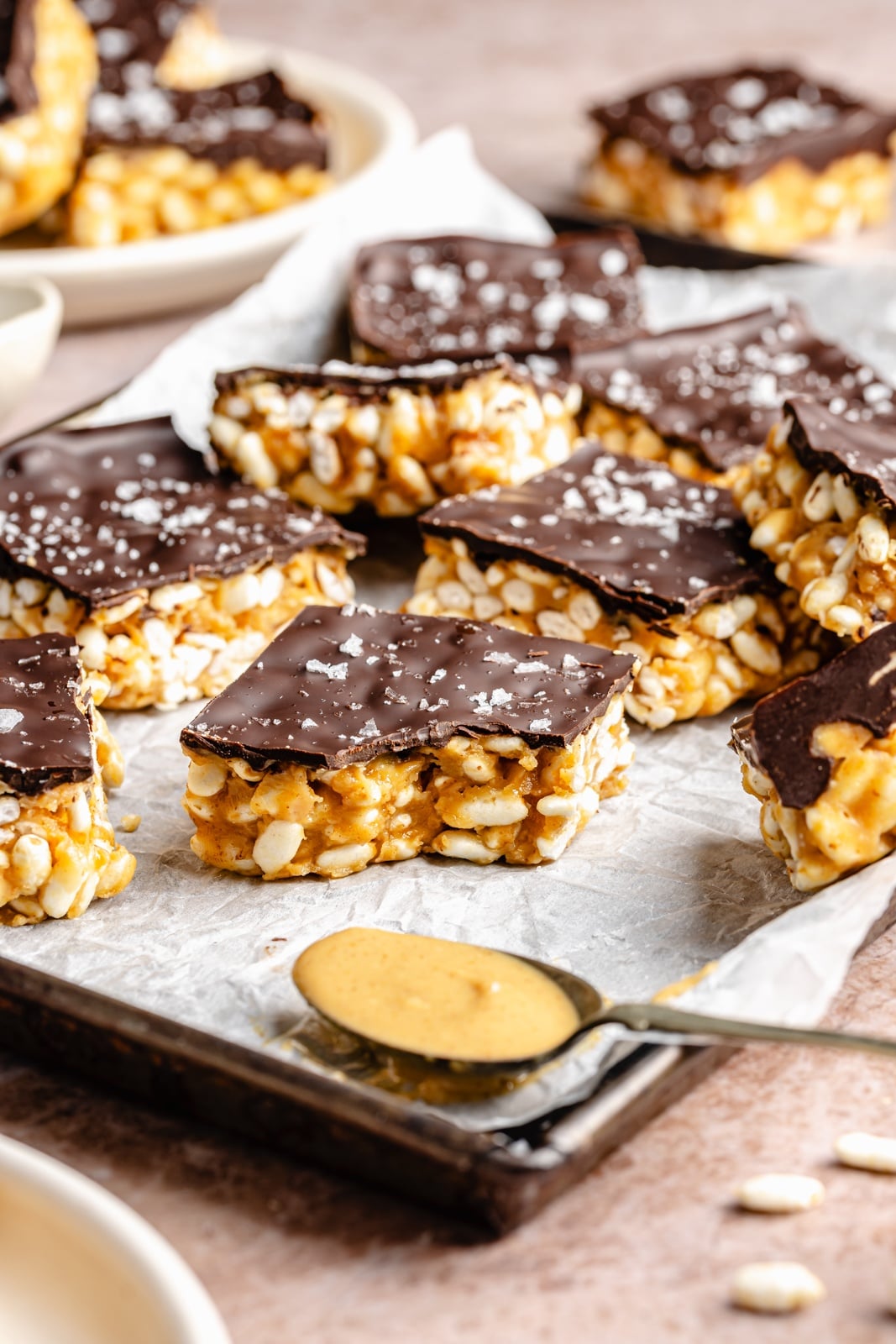 Healthy rice krispie treats made without marshmallows and with peanut butter, coconut oil, maple syrup, and brown rice krispies. These vegan and gluten-free peanut butter rice krispie treats are topped with dark chocolate and sea salt for an indulgent treat that tastes just like a crunchy peanut butter cup. Options to add a bit of protein powder to make these a great post-workout treat! easy peanut butter rice krispie treats on a pan