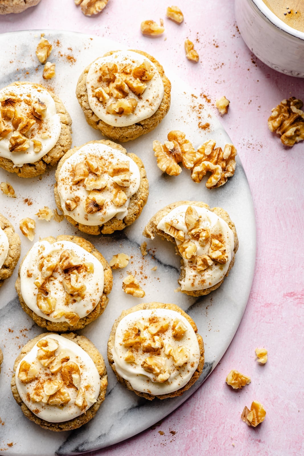 Soft, healthy banana cookies made with a mix of almond and coconut flour to make them gluten and grain-free! These banana bread cookies taste like a slice of your favorite banana bread and are topped with a luscious cream cheese frosting for a delicious treat everyone loves. grain-free banana cookies with frosting on a marble board