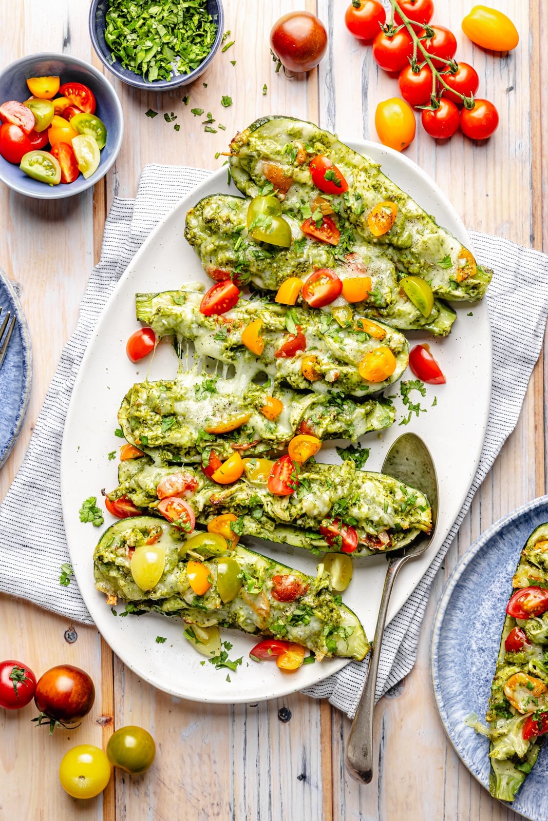 pesto chicken stuffed zucchini on a platter with cherry tomatoes