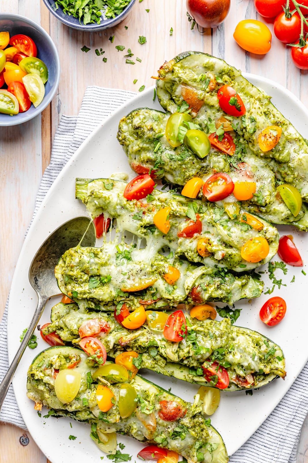pesto chicken stuffed zucchini on a platter with tomatoes