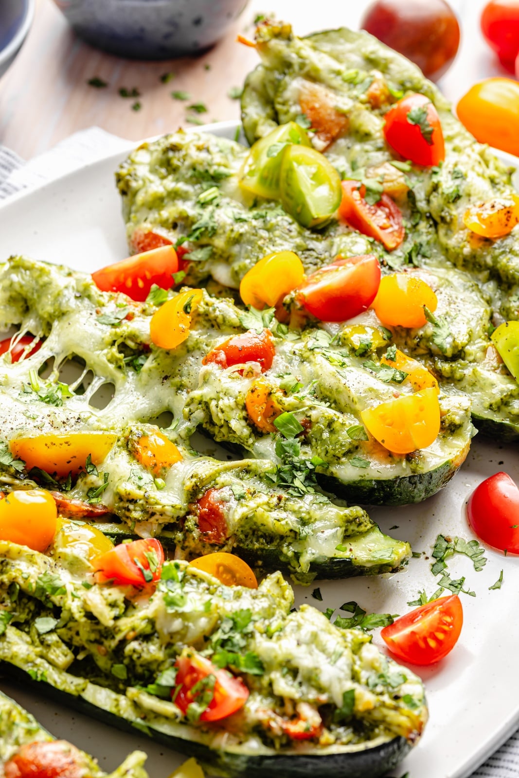 healthy pesto chicken zucchini boats with tomatoes on a platter