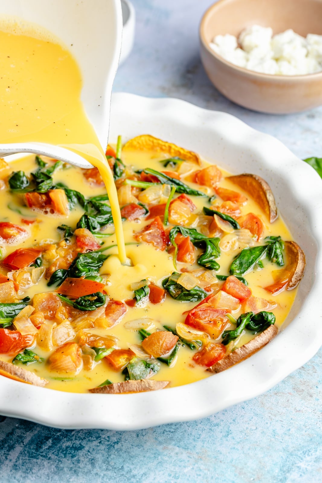 pouring eggs into a pan for a sweet potato crust quiche