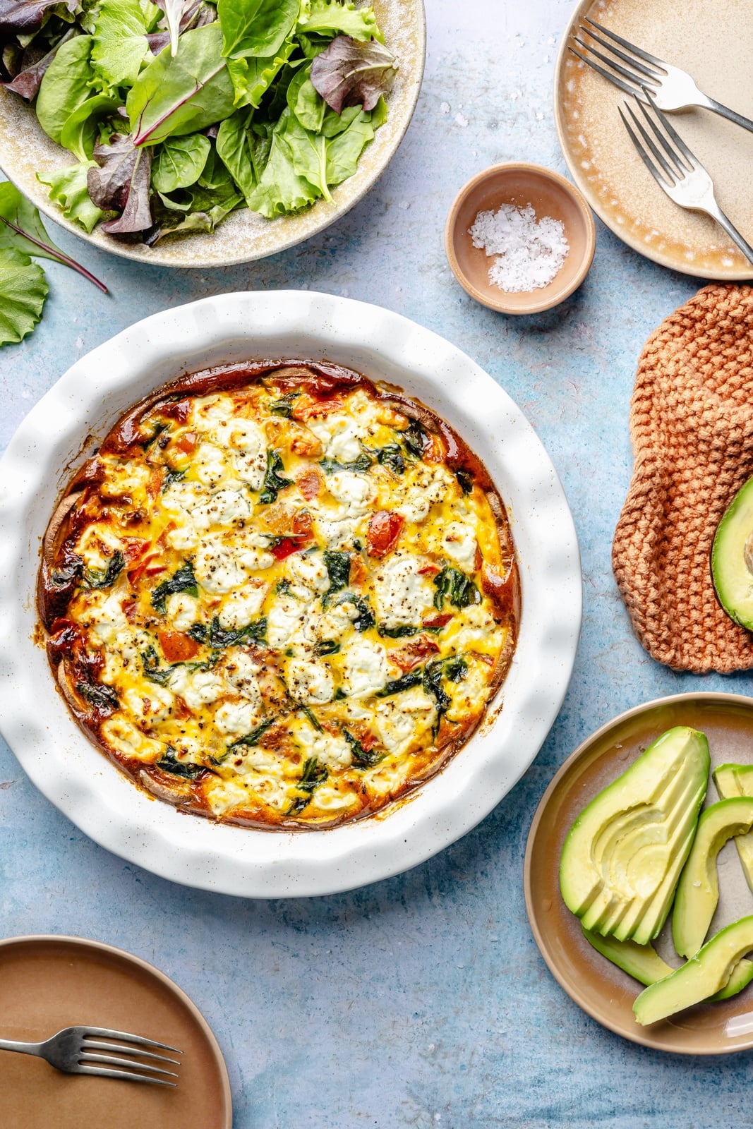 sweet potato crust quiche with spinach and goat cheese next to a plate of salad