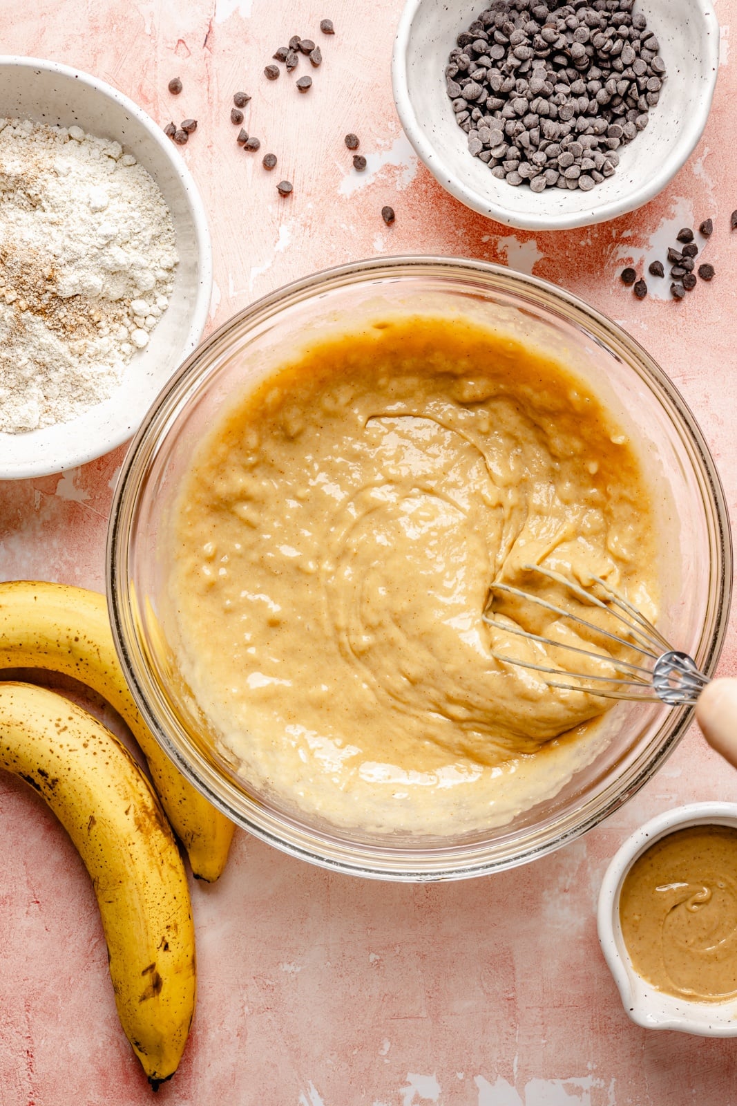 Healthy peanut butter banana muffins packed with protein and peanut butter flavor. These gluten-free peanut butter banana muffins are naturally sweetened with pure maple syrup, dairy-free, and a great on-the-go healthy breakfast or snack. Try them with mini chocolate chips! mixing batter for peanut butter banana muffins