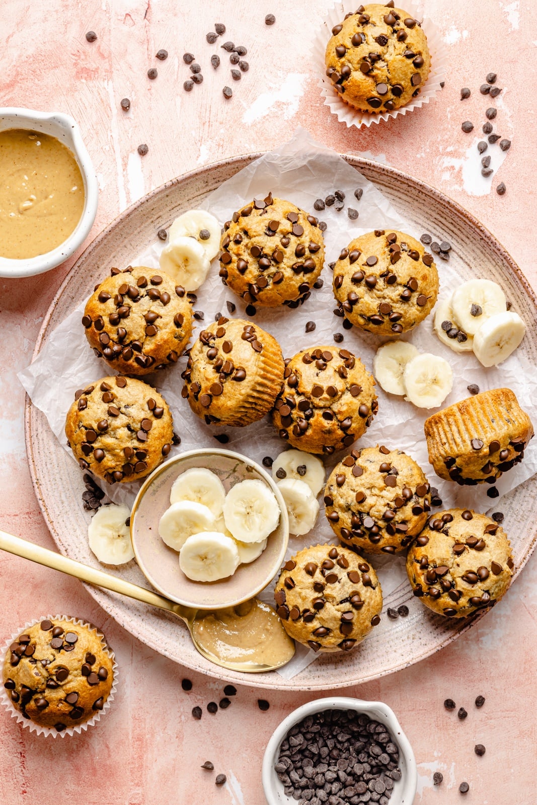 Healthy peanut butter banana muffins packed with protein and peanut butter flavor. These gluten-free peanut butter banana muffins are naturally sweetened with pure maple syrup, dairy-free, and a great on-the-go healthy breakfast or snack. Try them with mini chocolate chips! gluten-free peanut butter banana muffins on a tray with sliced bananas
