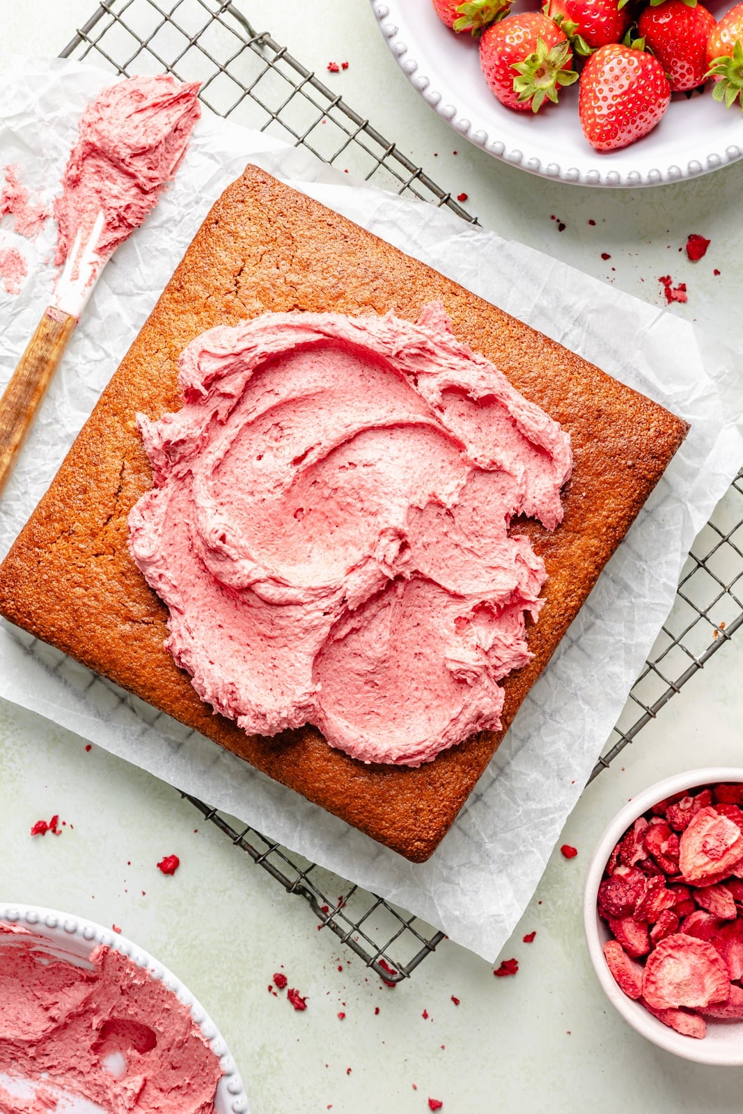 topping a strawberry snacking cake with strawberry frosting