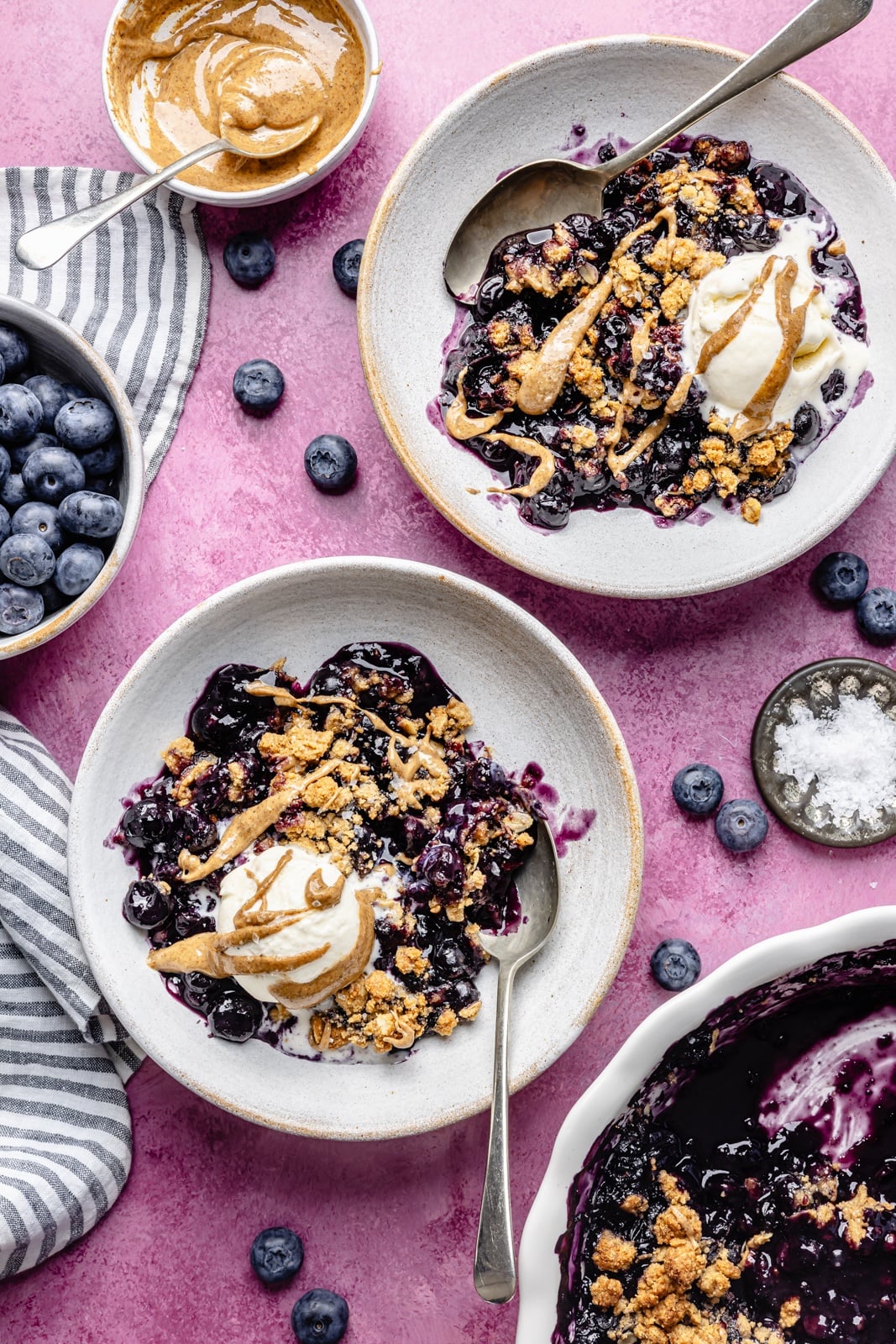 Golden, bubbly blueberry crisp with a perfectly sweet almond butter crumble. This delicious blueberry crisp recipe is easily made gluten-free, dairy-free, and vegan, and makes the perfect summer dessert for sharing. Add a scoop of vanilla ice cream and a drizzle of extra almond butter for good measure! healthy blueberry crisp in two bowls with ice cream