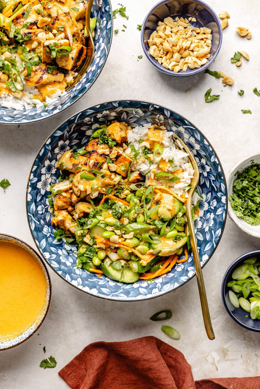 High-protein grilled peanut chicken bowls with edamame cucumber salad and an extra drizzle of flavorful peanut sauce. Assemble these peanut chicken bowls with fluffy rice or quinoa, roasted peanuts, and fresh garnishes for a delicious summer weeknight dinner you'll crave! grilled peanut chicken bowls with rice and edamame salad